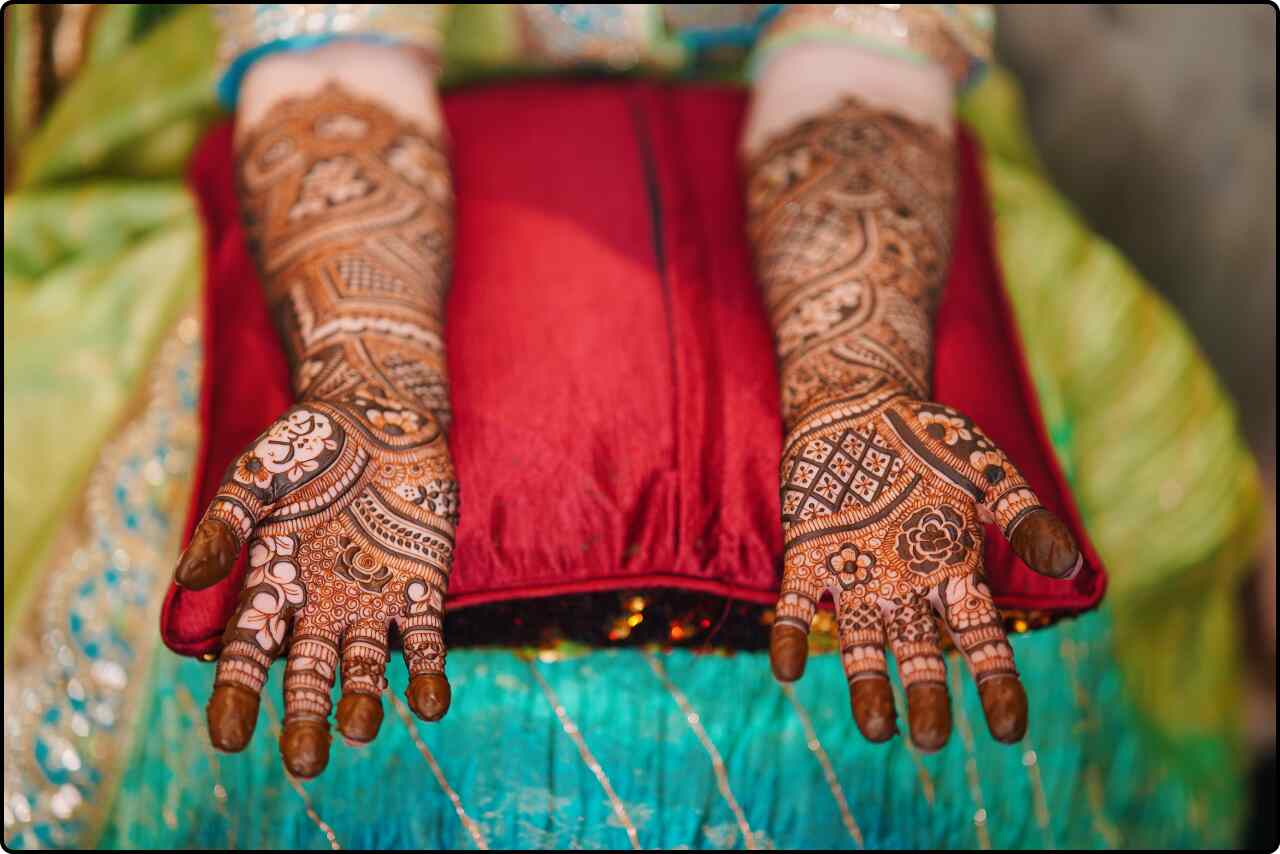 Close-up of a woman's hands adorned with intricate henna designs on her palms and fingers.